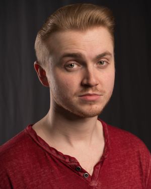 Headshot of person in red henley shirt with styled blonde hair.