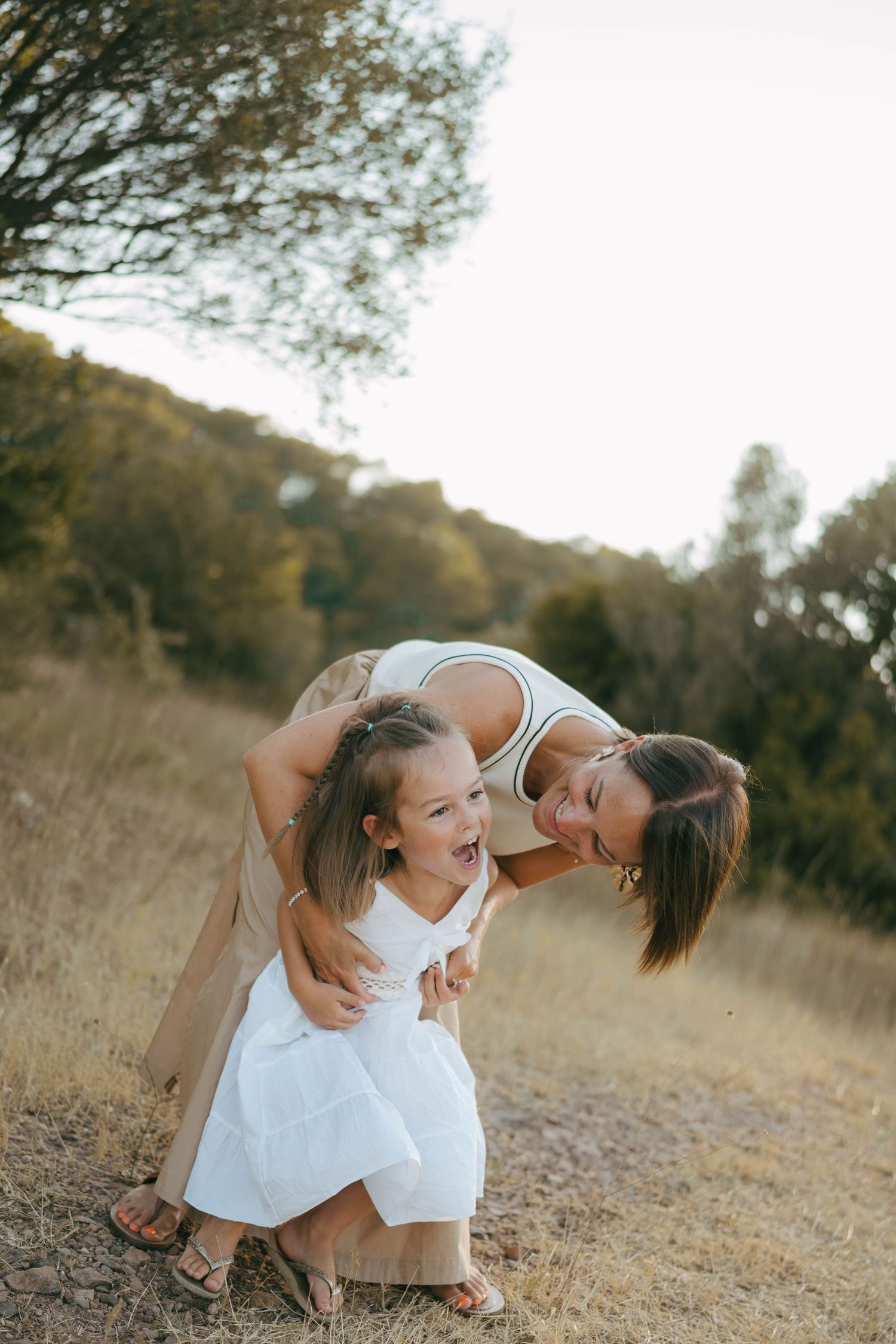 A joyful duo shares playful moments in a sun-drenched field at golden hour.