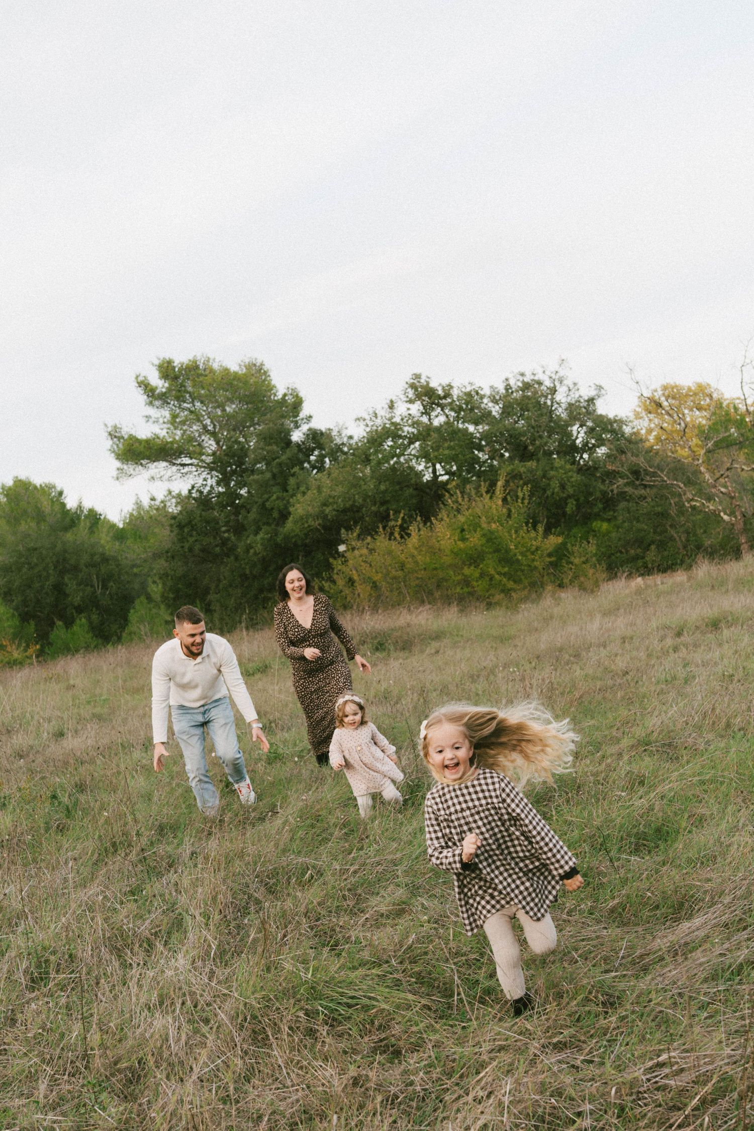 A group runs and plays together on a grassy hillside during a warm autumn afternoon.