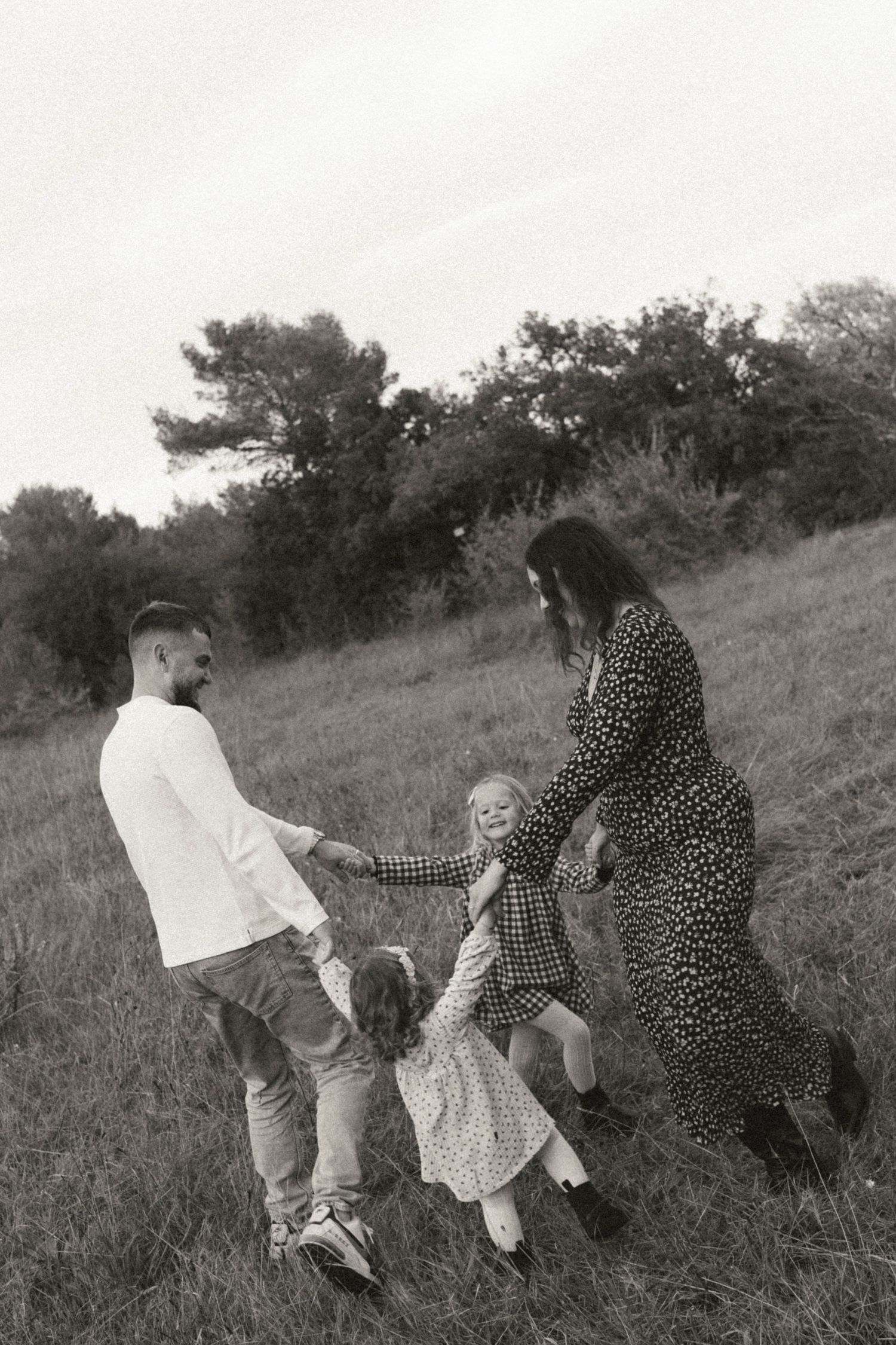 A sequence of three black and white photos showing people walking up a grassy hillside together.