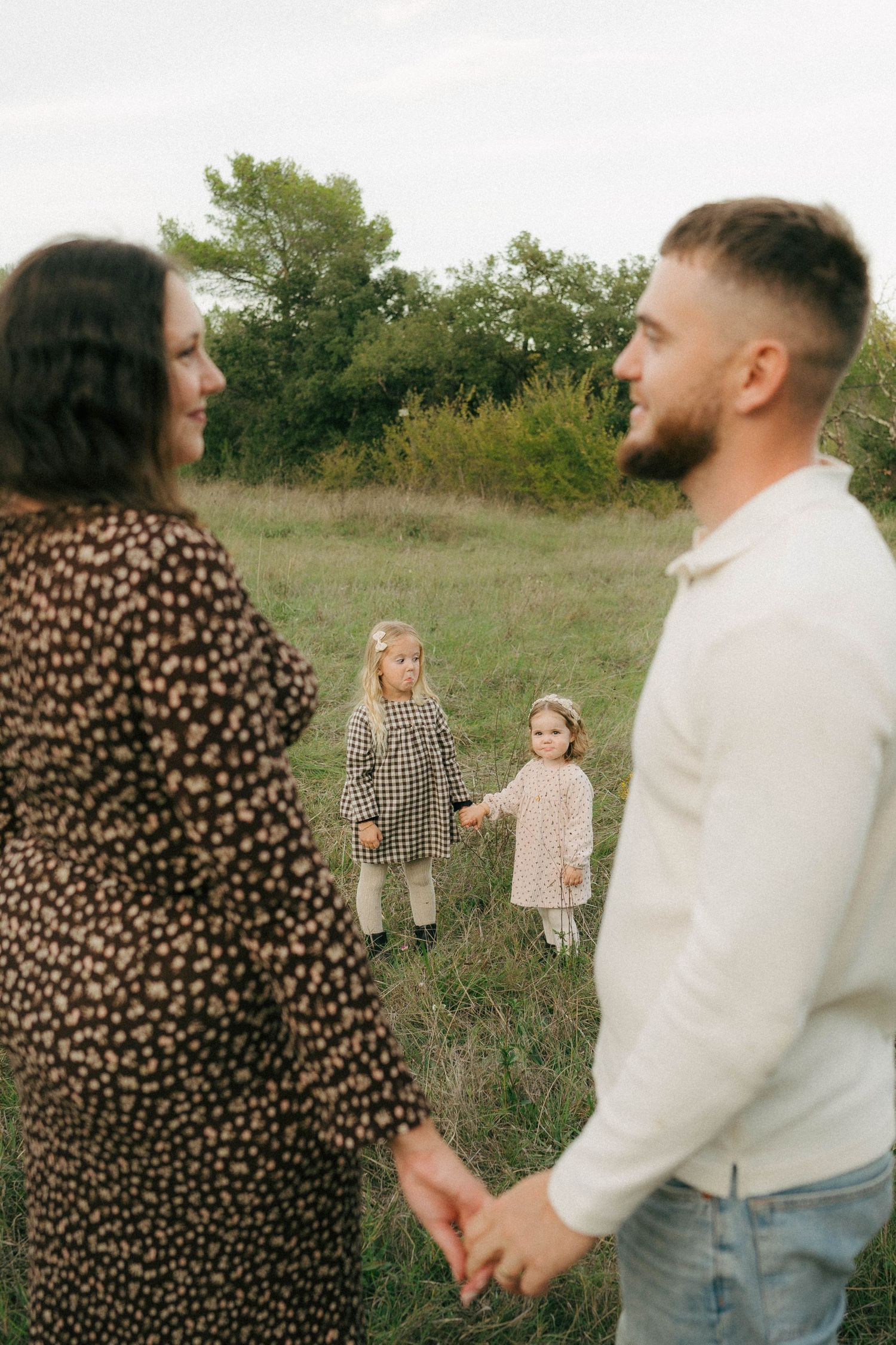 Family enjoying a candid outdoor photo session in a natural field setting at golden hour.