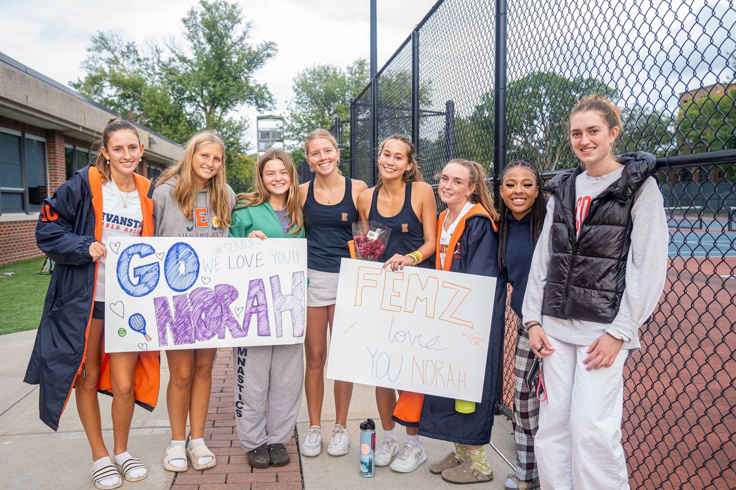 Group of students holding supportive signs outside school building.