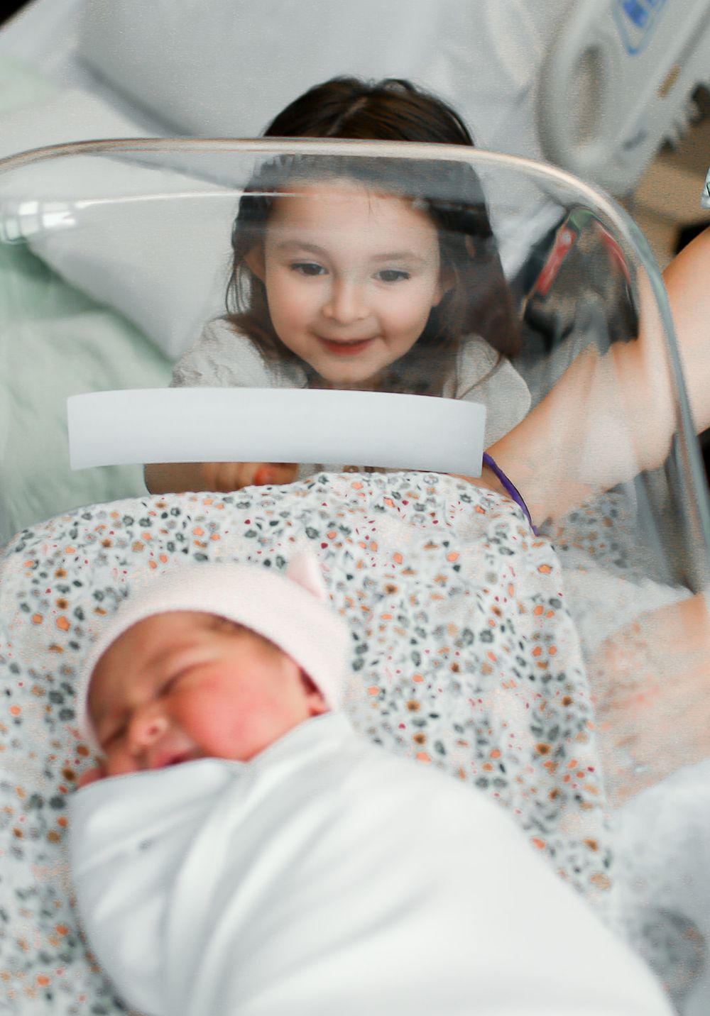 Big sister looking at newborn sister in hospital