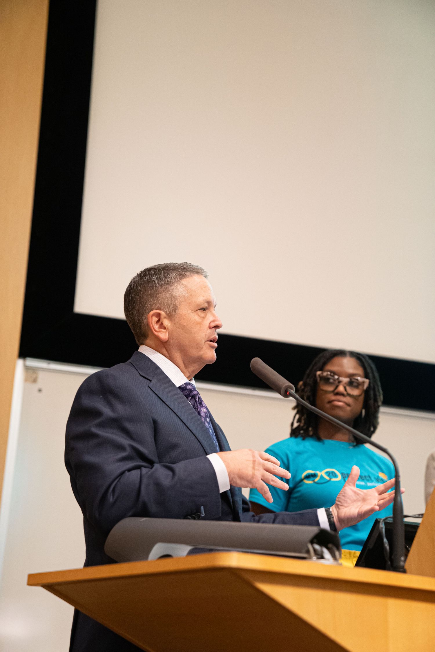 Speakers presenting at a podium during a professional conference event.