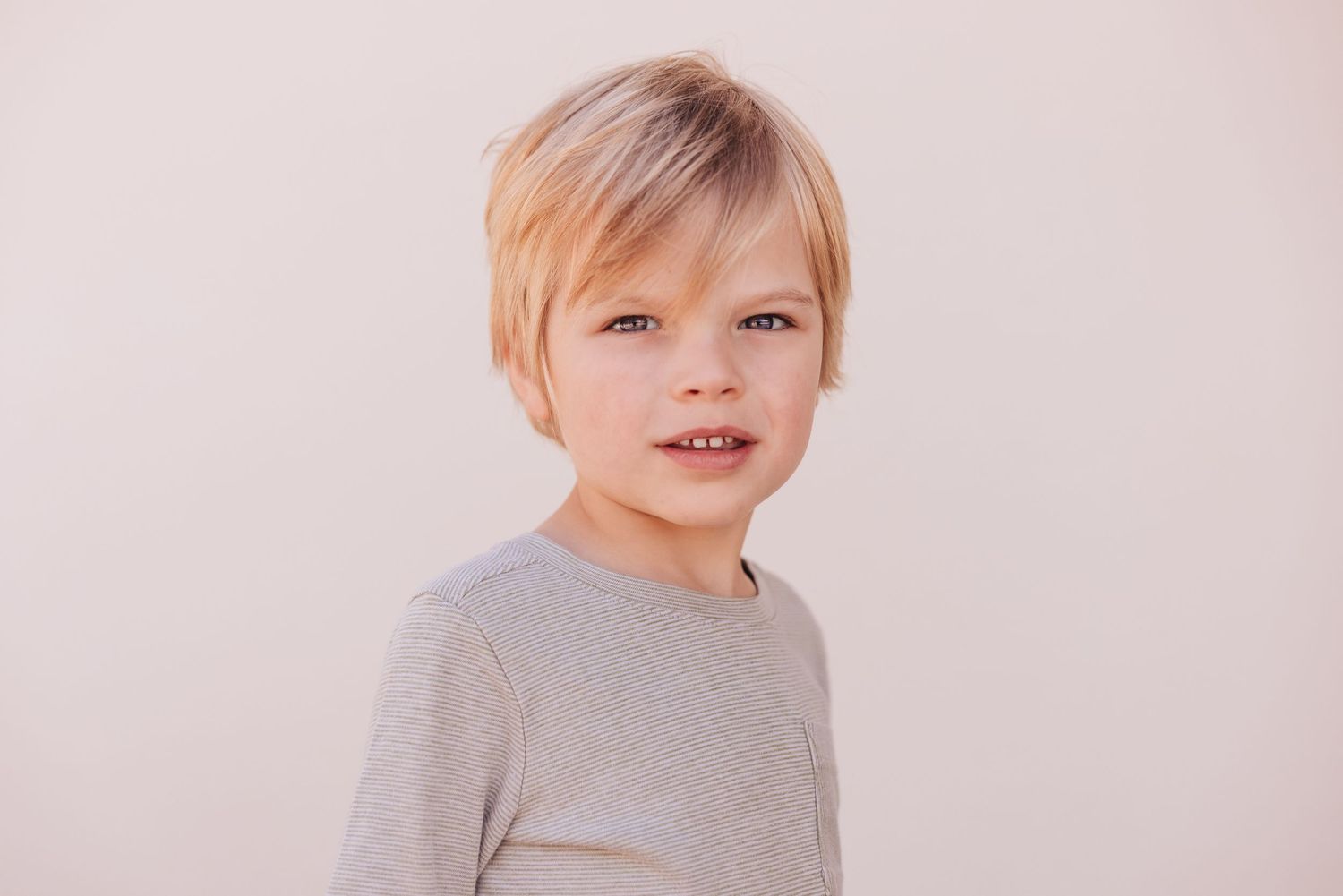 A joyful young child in a long sleeve shirt making a playful expression while holding their hands near their face in black and white.