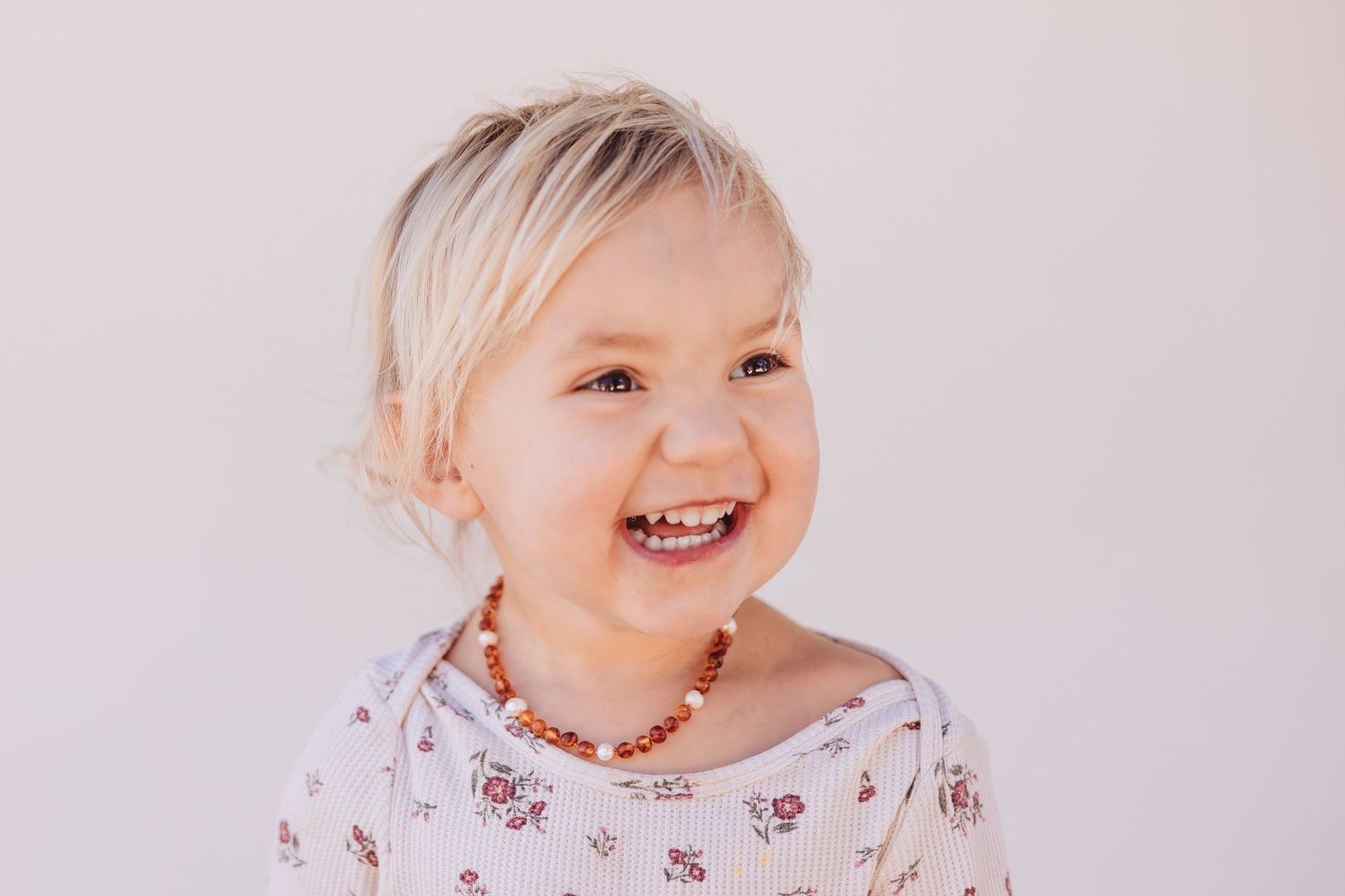 A joyful young child in a long sleeve shirt making a playful expression while holding their hands near their face in black and white.