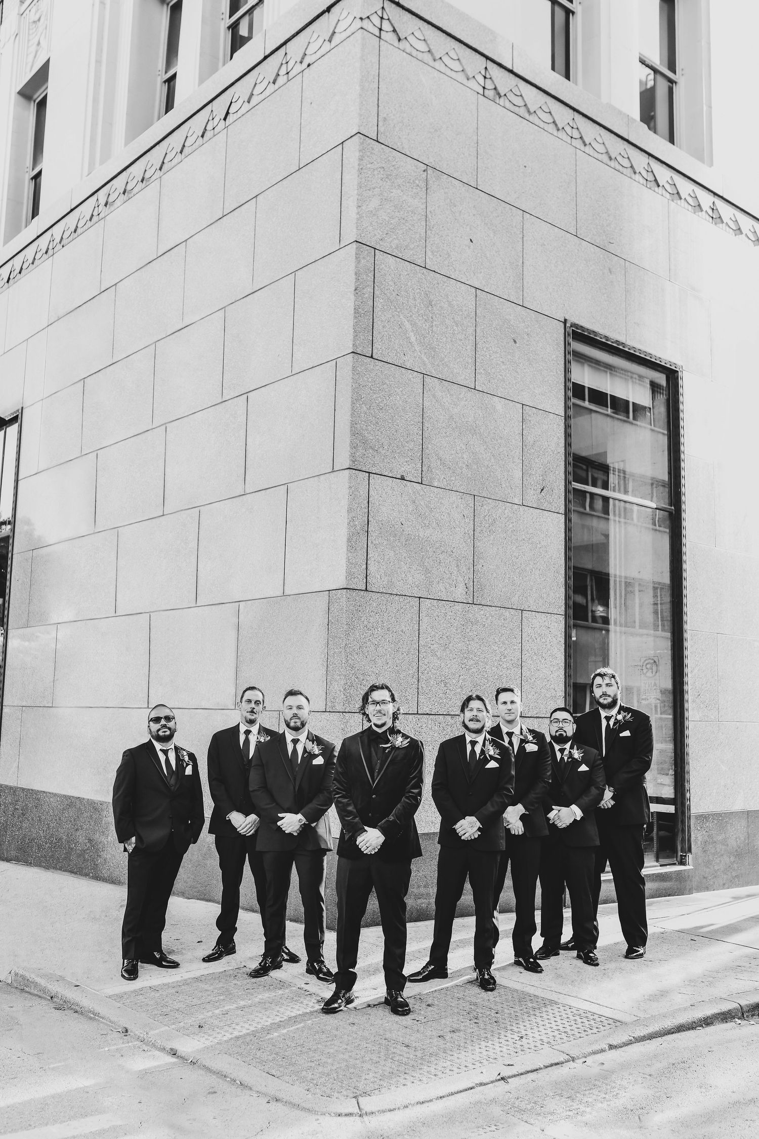 a black and white photo of the groom and his crew posing for photos in downtown dallas