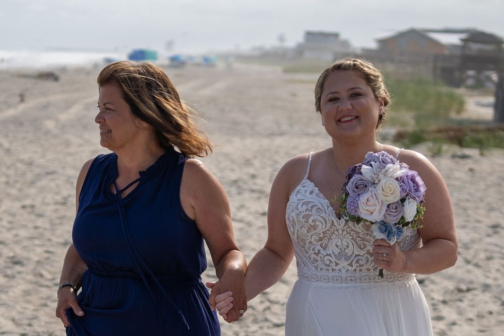 Candid moments between people walking along a sandy beach at sunset under partly cloudy skies.