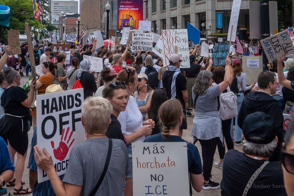 Protesters hold signs during a demonstration against state laws limiting medical care in front of a building.