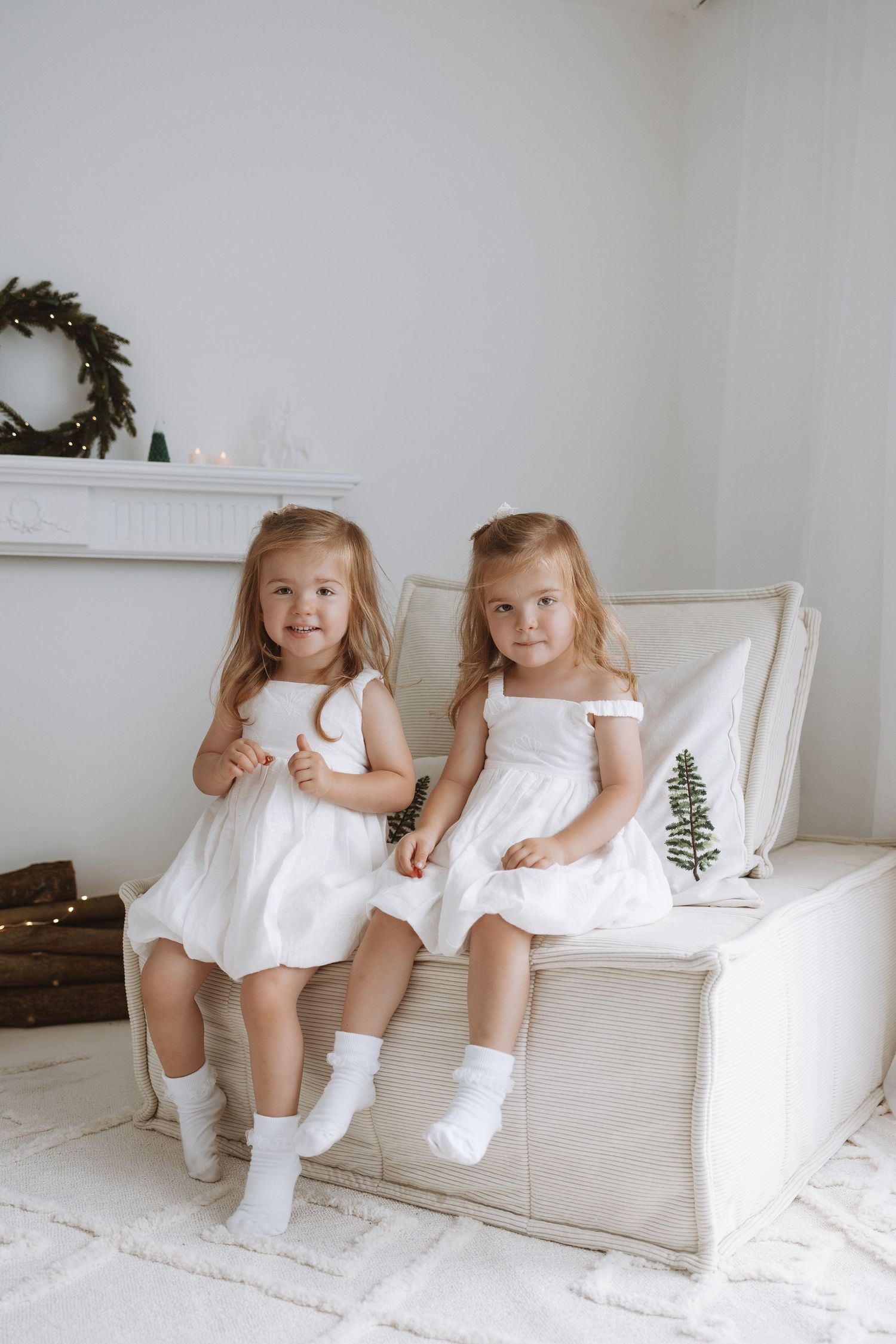 Black and white portrait of an adult and young child sitting together in a white chair with balloons visible in background.