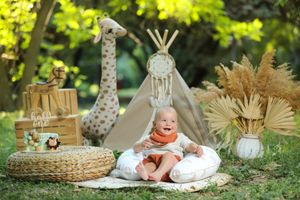 Safari themed first birthday setup outdoors with teepee, wooden decor and natural lighting.