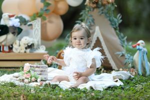 Boho-inspired outdoor photo setup with white feathers and natural garden backdrop.