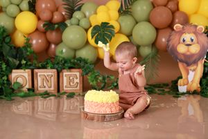 Safari-themed first birthday setup with cake, blocks, and balloon decorations.