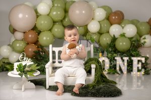 Green and white balloon arch with ONE lettering for first birthday photoshoot.