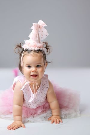 Sweet first birthday photo session featuring pink tulle dress and bow accessories.
