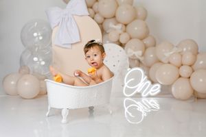 Pink and white balloon garland setup for cake smash photography session.