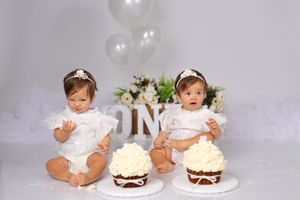 White and cream colored cake smash photography setup with floral accents.