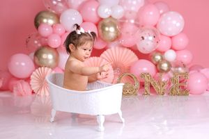 Pink and gold balloon arch backdrop for birthday celebration photoshoot.