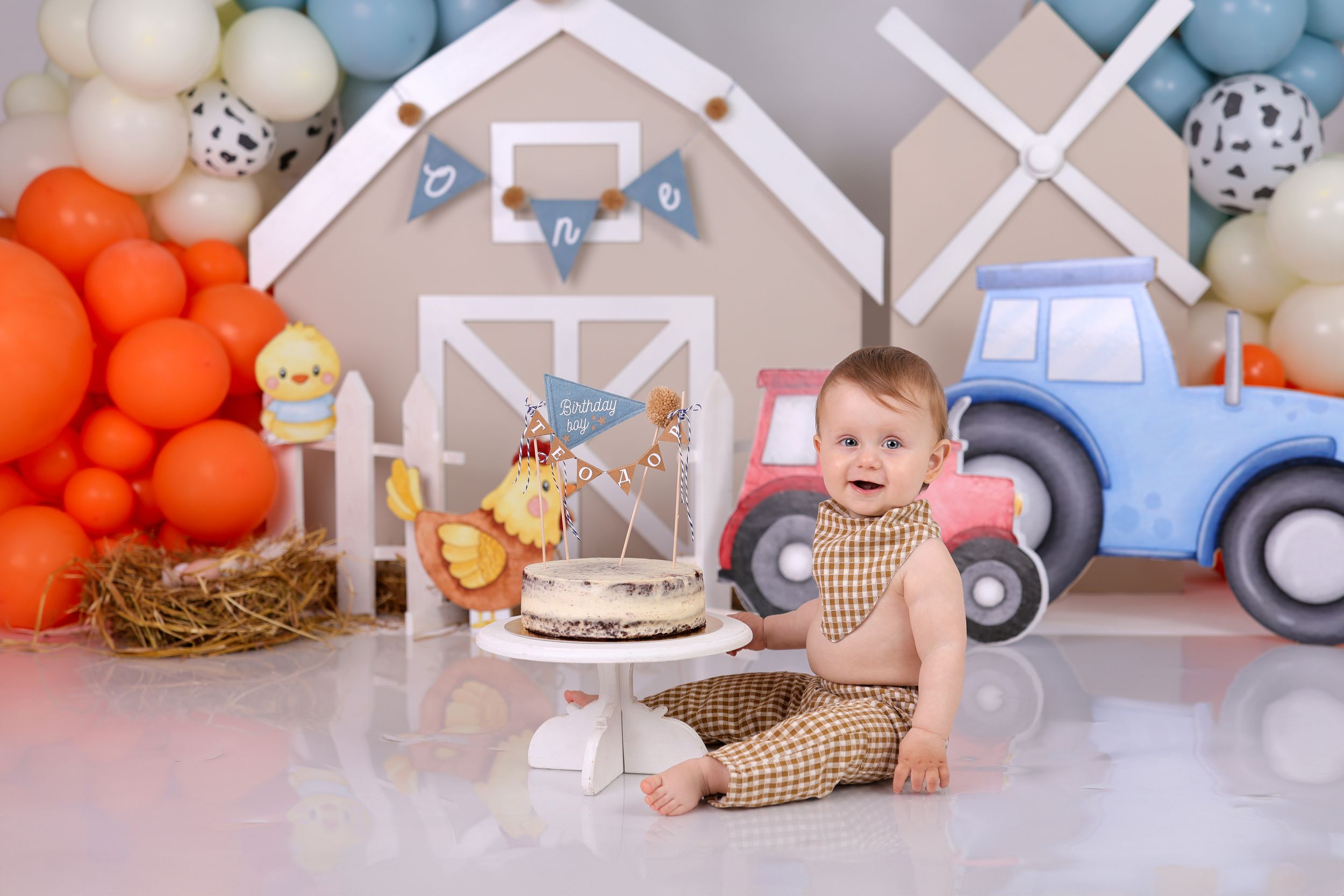 Modern farmhouse themed birthday setup with toy cars and white house decorations.
