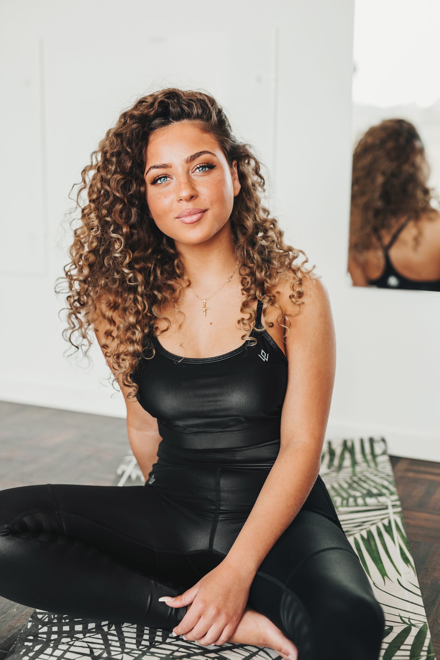 Avslappnat porträtt av Emelie Battah i svarta träningskläder sittandes på en yogamatta på ett event i Stockholm på Clarion Hotell