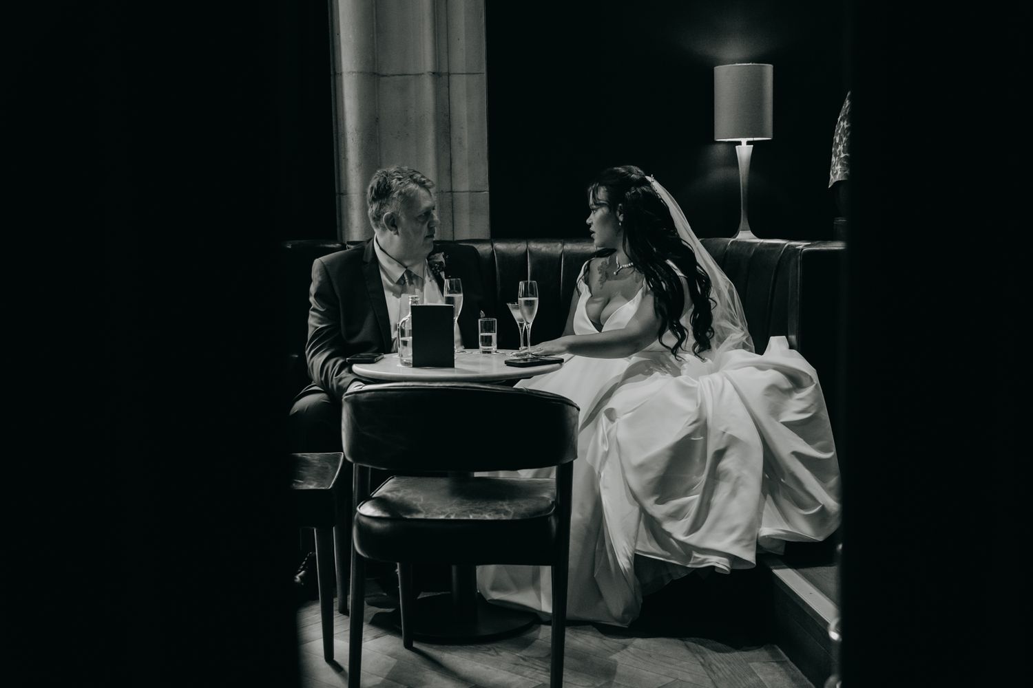 Black and white photo series showing someone seated at small tables in a dimly lit restaurant interior.