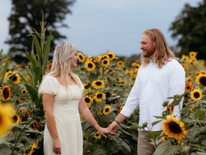 Romantic Couple poses in a sunflower field wearing coordinating white and beige outfits. Timeless love stories and true to color photography