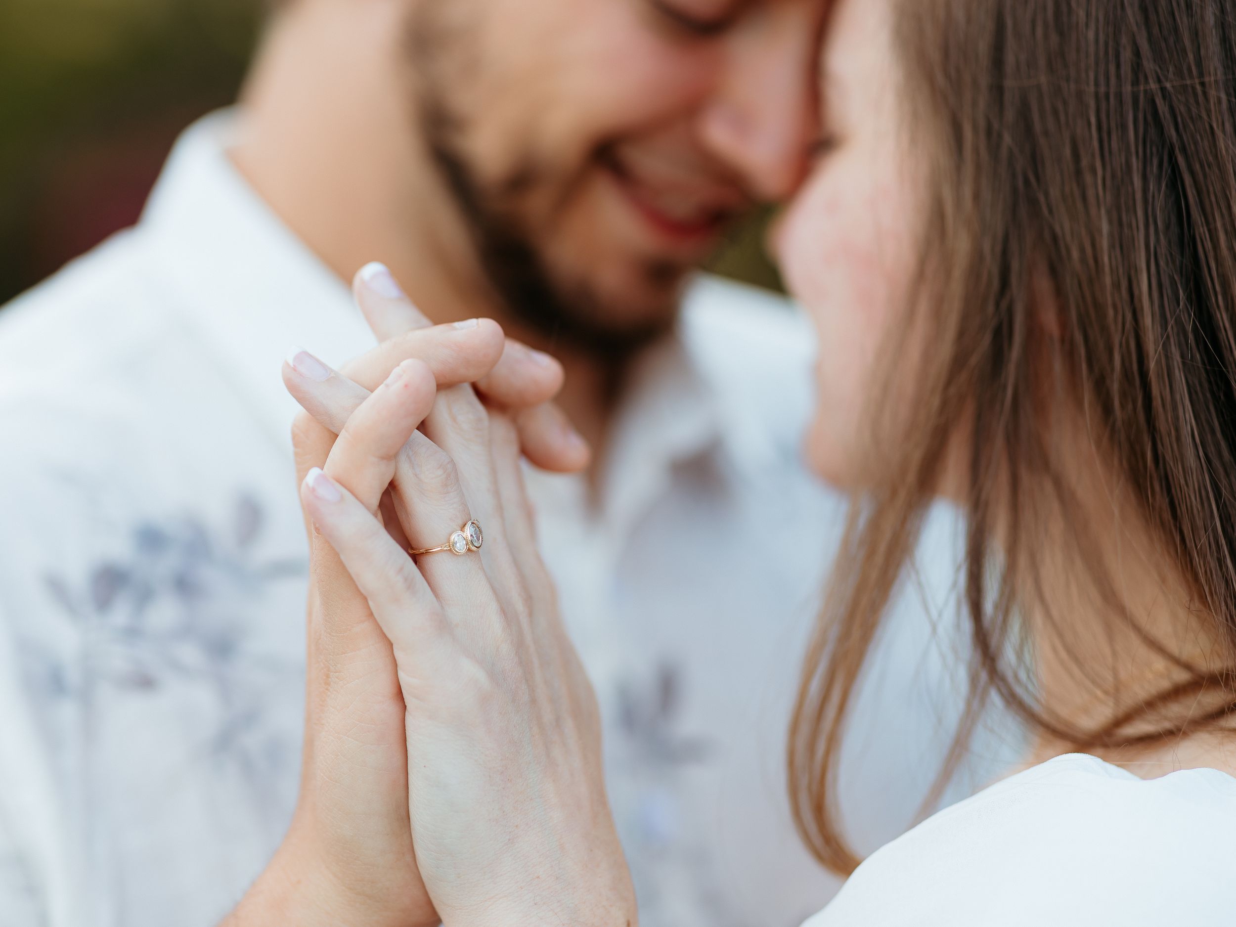 Intimate close-up of couple holding hands with engagement ring.