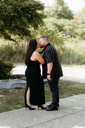 Couple sharing romantic moment on outdoor path wearing black formal attire. Candid documentary couples photography session.