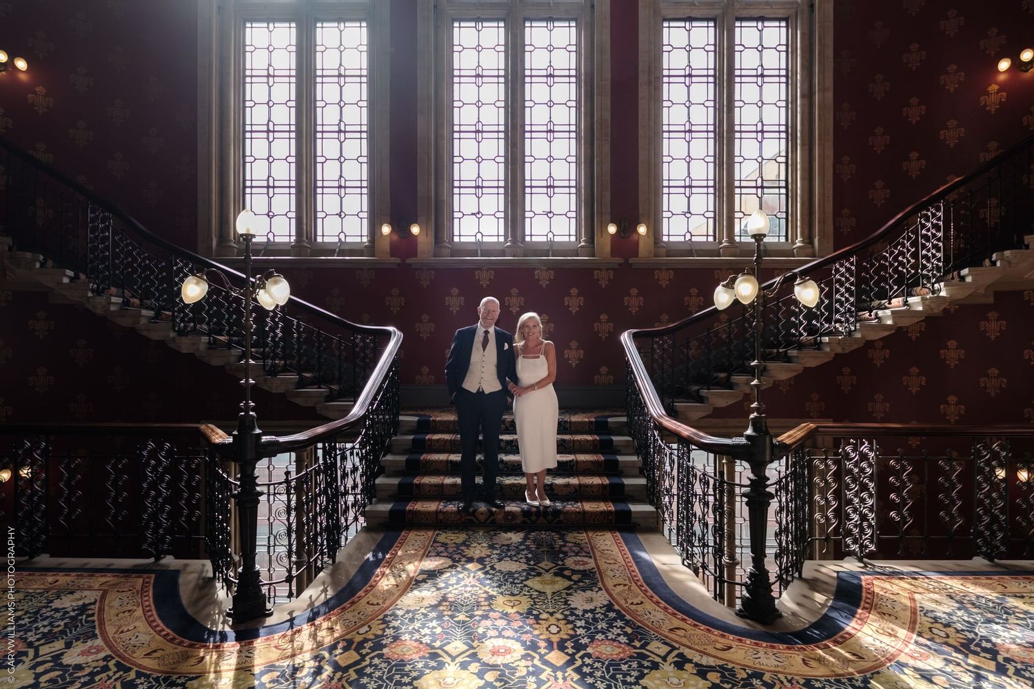 Elegant grand staircase in historic mansion with ornate iron railings and window-lit landing creates dramatic architectural view.