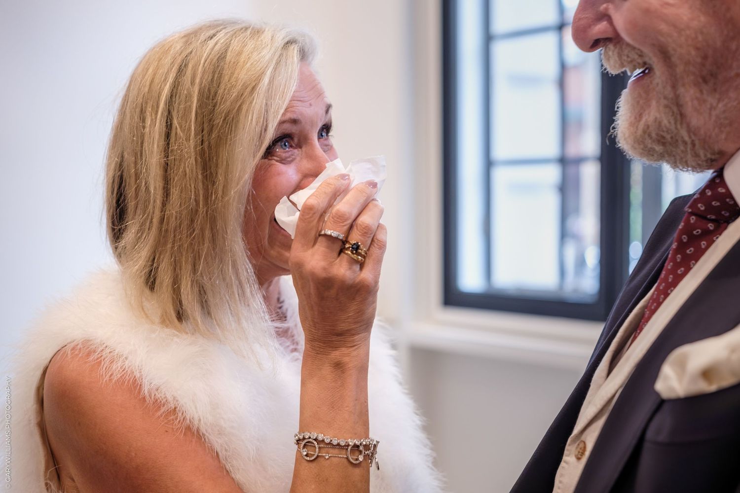 Wedding guests laugh and smile together during a reception in a bright, modern indoor venue.