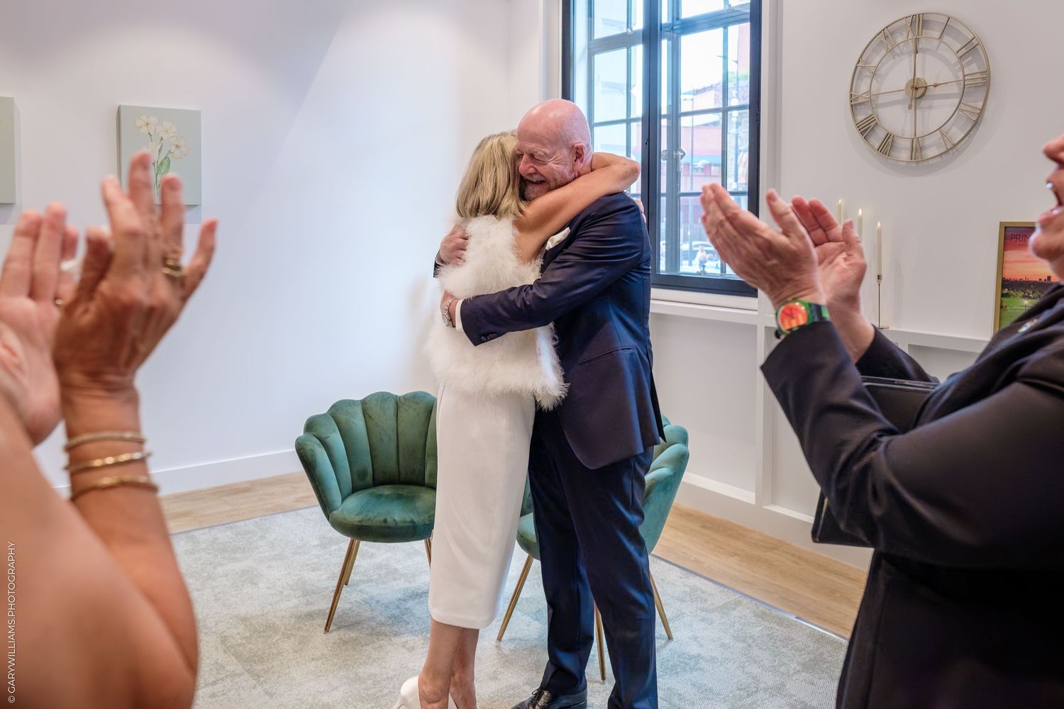 Two people share a romantic dance and embrace in a bright sunlit room with elegant decor and hardwood floors.