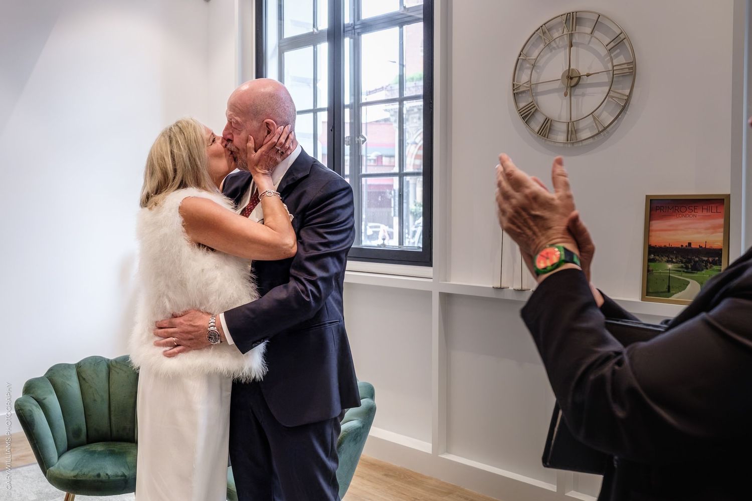 A composite photo shows five frames of a couple in formal attire dancing in a bright white room with a clock on the wall.