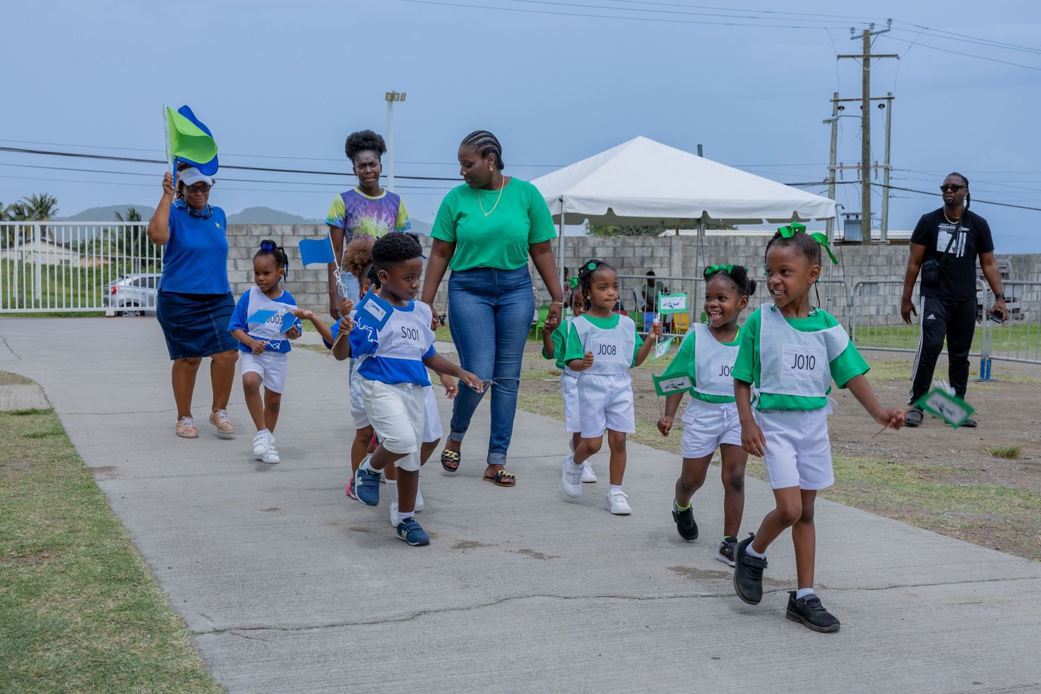 Children from Baptist Academy's Blue Jets and Green Rockets entering during Sports Day at the Antioch Baptist Church grounds in St. Kitts.