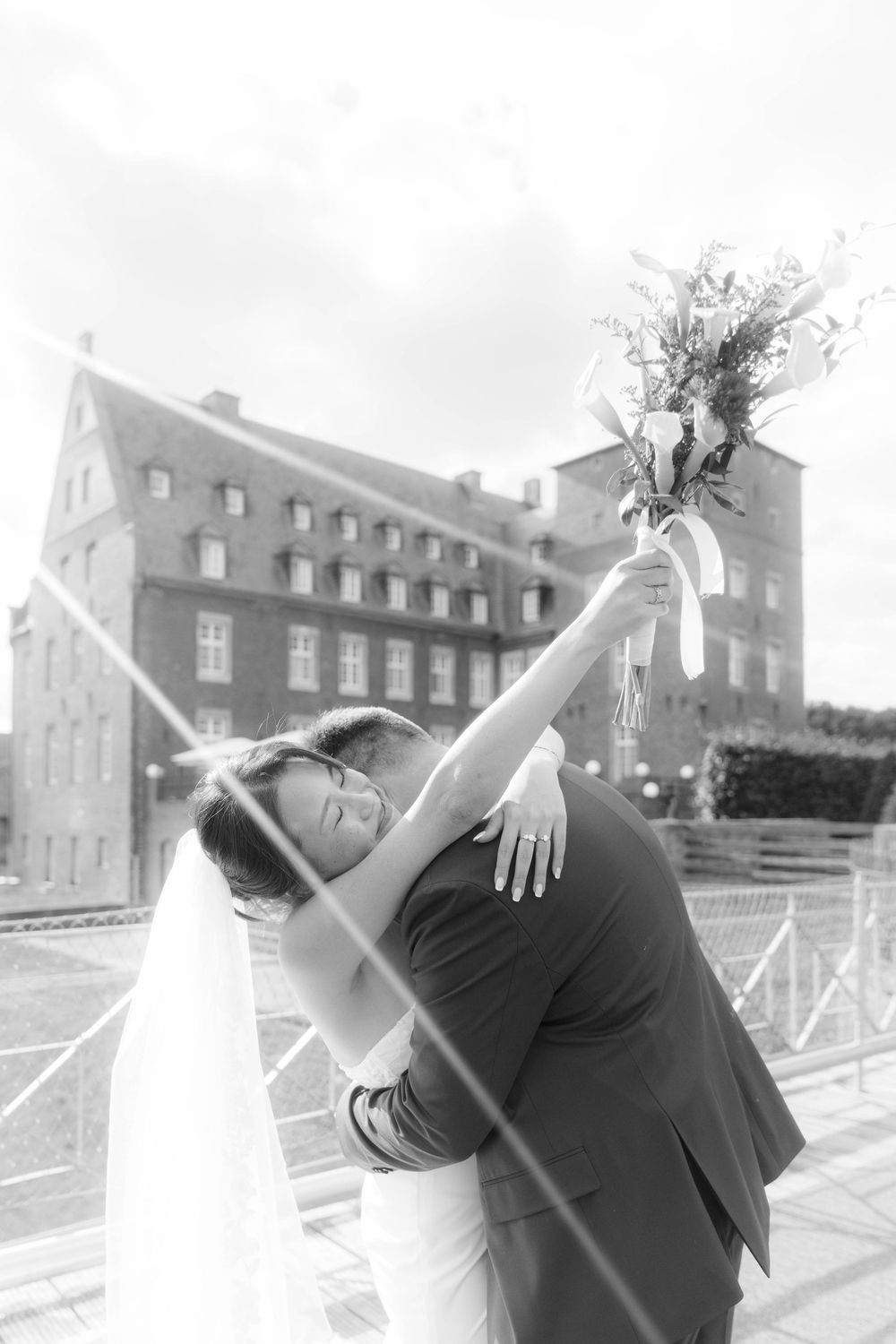 A romantic dip pose between newlyweds in front of a historic brick building.
