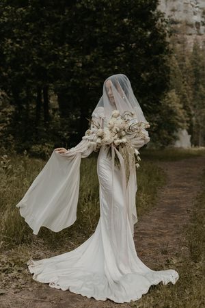 Four artistic photographs of a flowing white wedding dress moving gracefully in the wind on an outdoor woodland path.