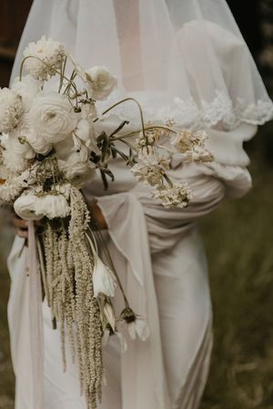 Elegant white bridal bouquets with cascading flowers and delicate foliage against white wedding dresses.