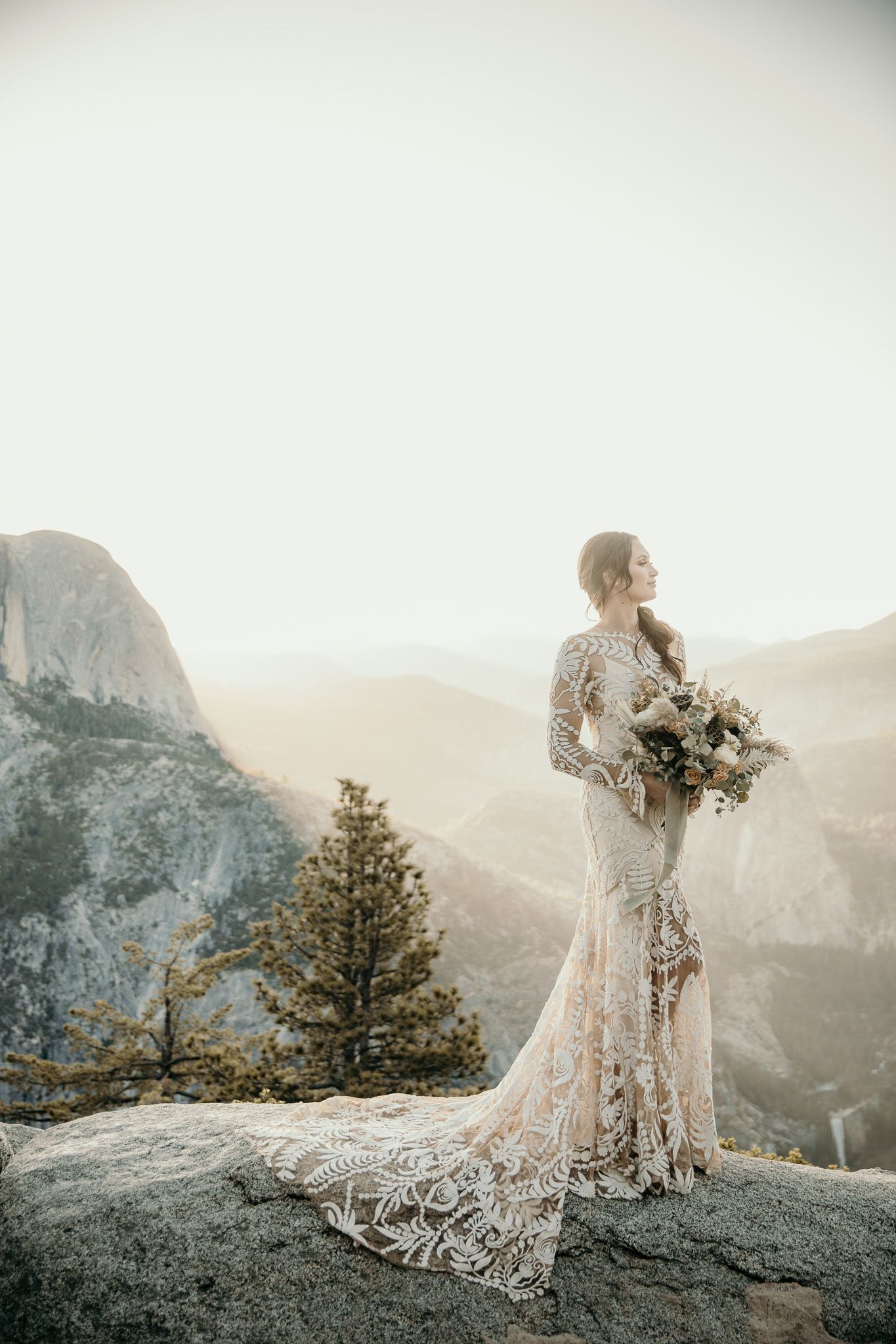Scenic mountain landscape view of Yosemite Valley with elegant white dress flowing in the breeze at sunset.