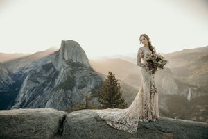 Scenic mountain vista in Yosemite National Park with dramatic cliffs and hazy golden sunlight in the background.