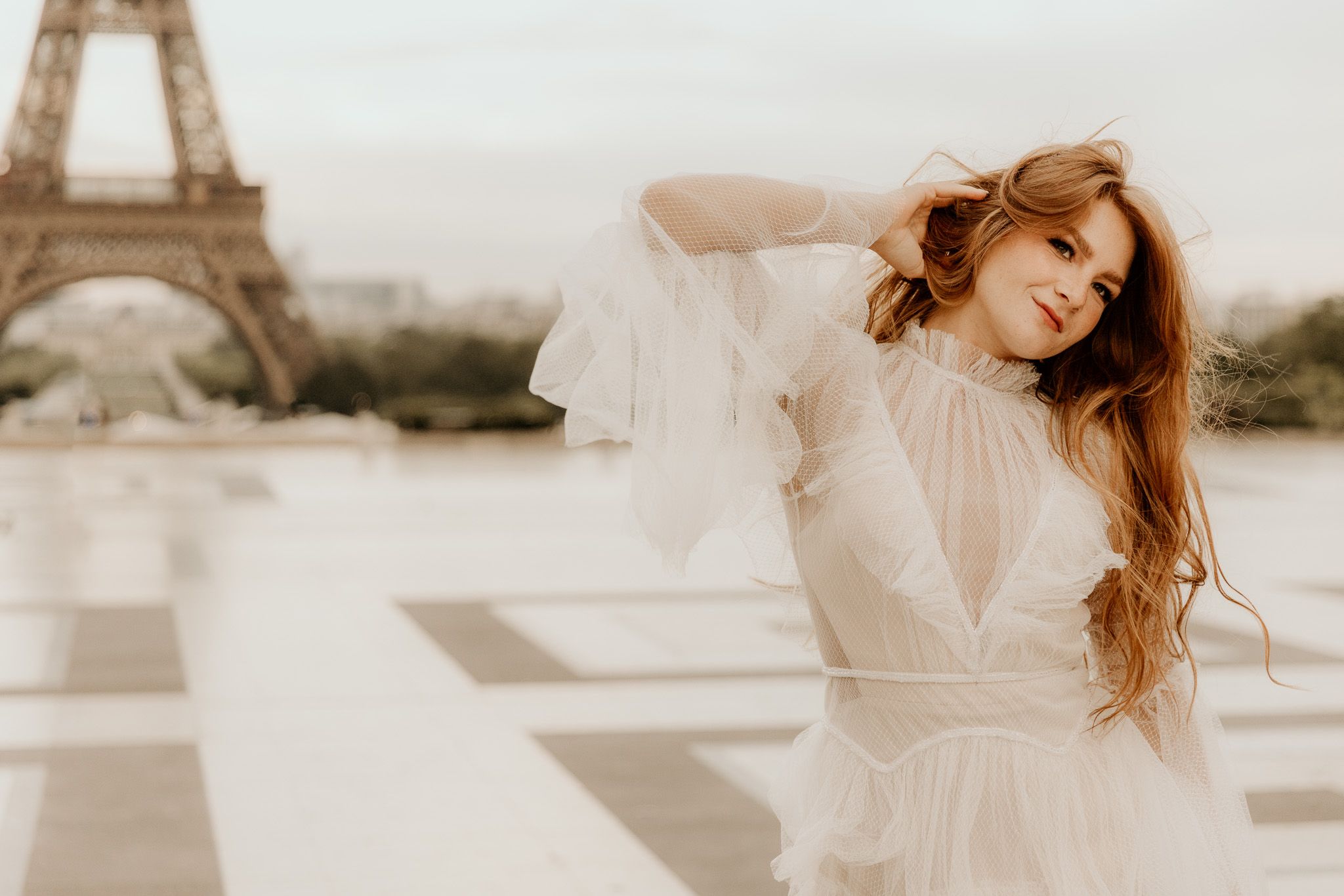 Ethereal bridal session in flowing white dress with Parisian backdrop in dreamy lighting.
