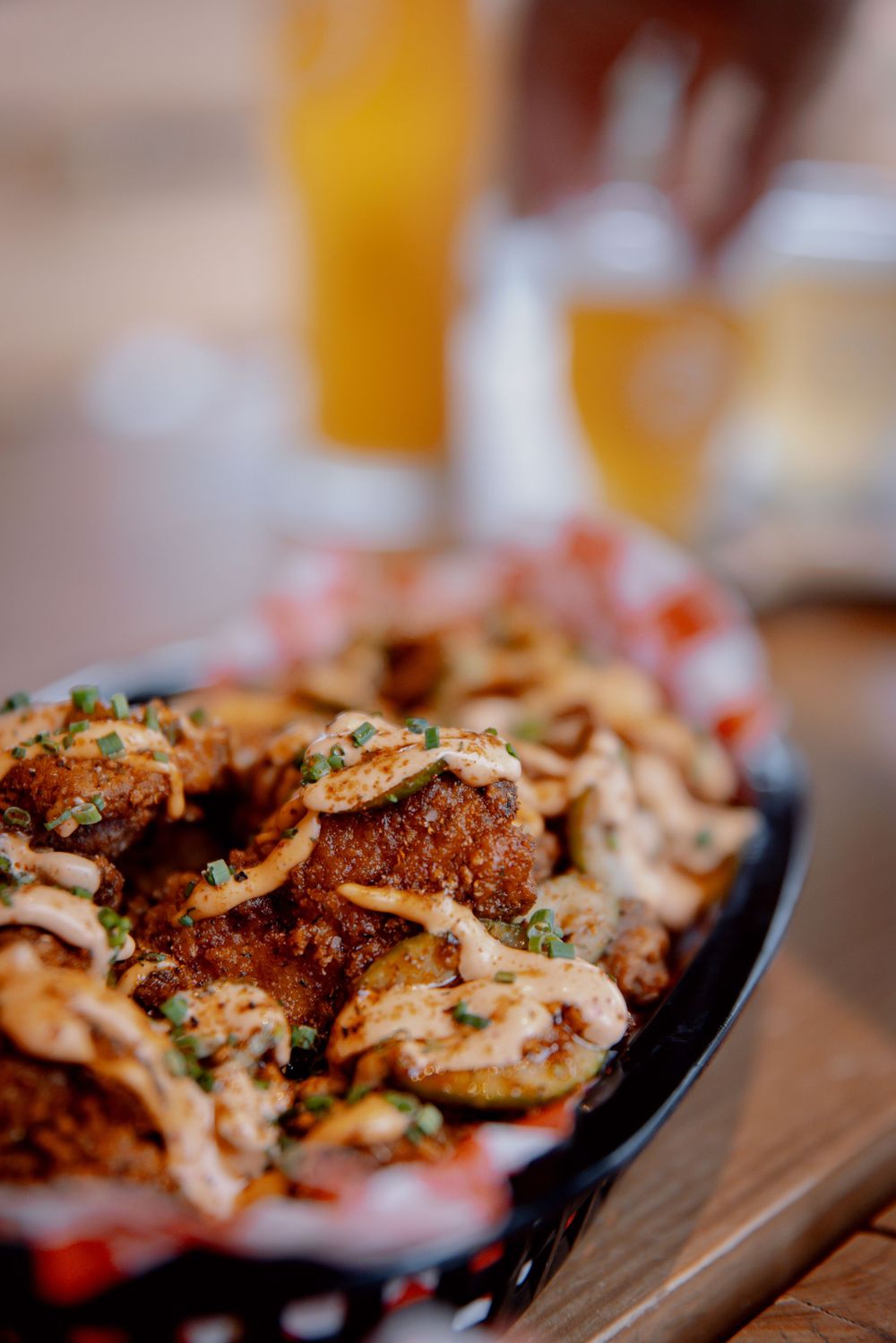 Close-up view of grilled chicken pieces garnished with fresh herbs served on a black plate.