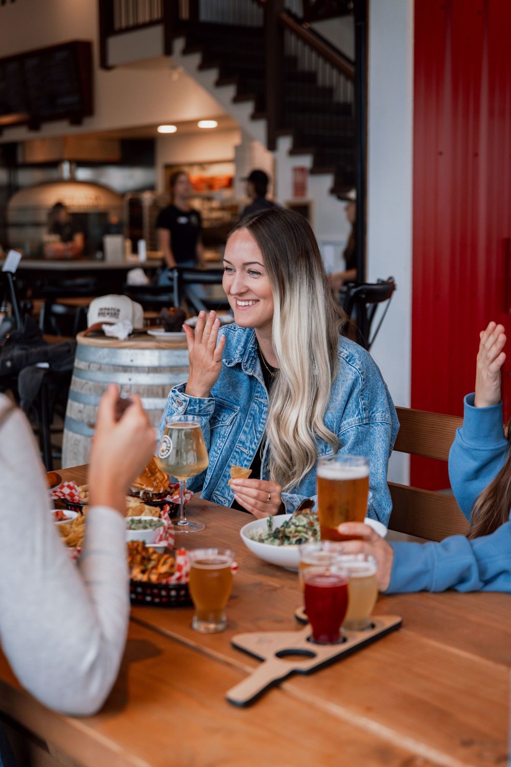Friends enjoying drinks and conversation at a restaurant with wooden tables and beers on a casual evening out.