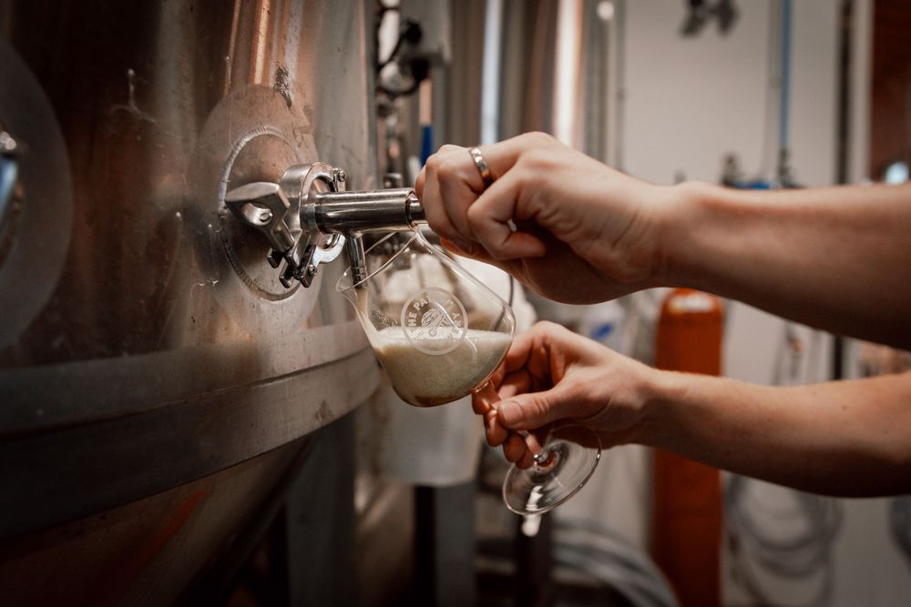 A hand pulls fresh espresso shots from a professional coffee machine into small white ceramic cups.