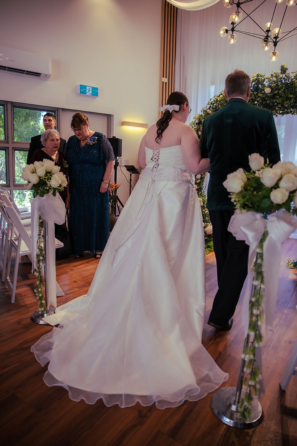 White wedding gown adorned with organza layers swirls elegantly across a wooden dance floor during a reception.