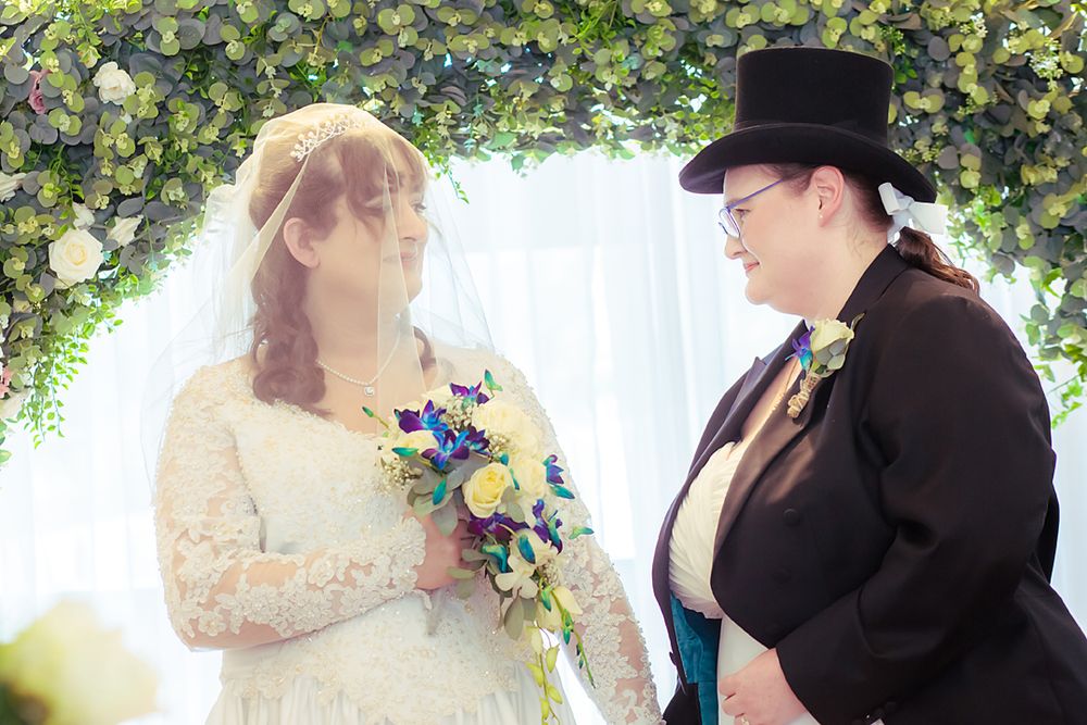 A dove is released during a sunny outdoor wedding ceremony while the couple shares a romantic first kiss.