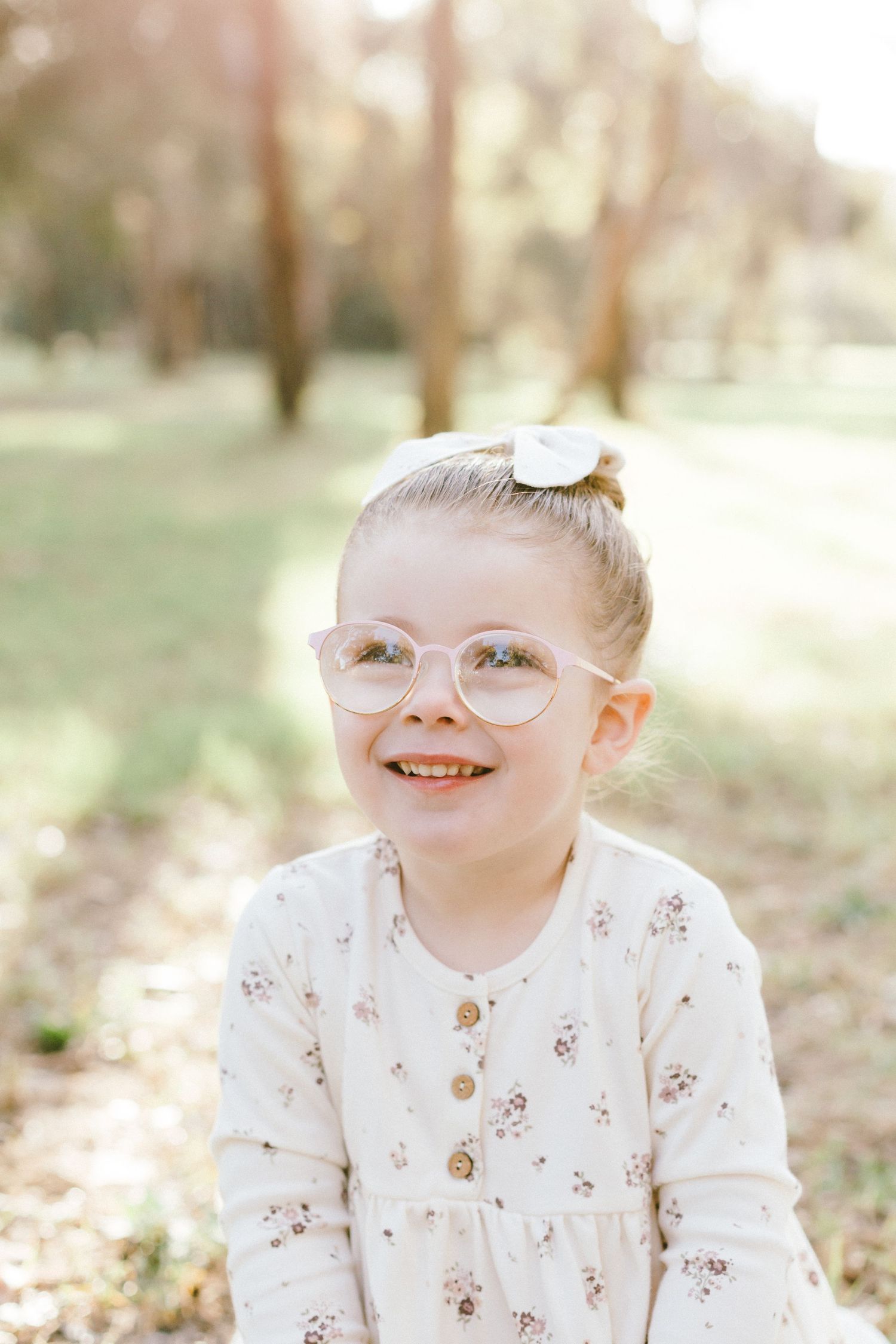 Three connected outdoor portrait shots featuring delightful expressions, white floral outfit and glasses in natural lighting.