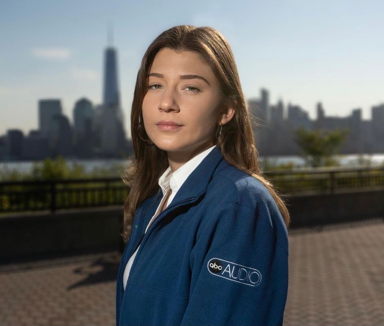 Professional headshots of client in blue jacket against city skyline background.