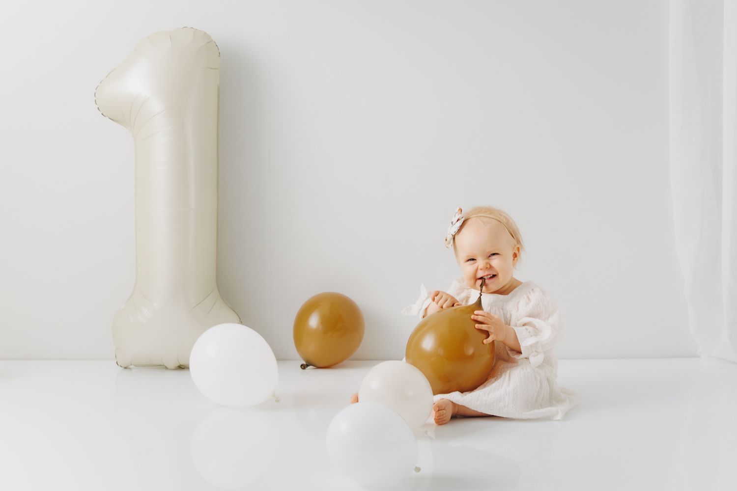Conceptual still life with broken ivory egg, spilled milk and round brown objects against white background.