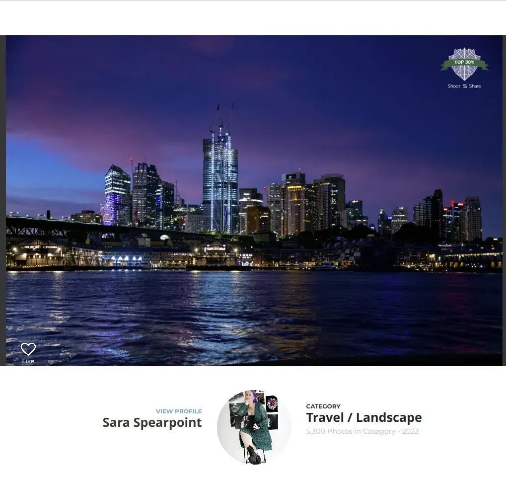 Night cityscape of illuminated skyscrapers reflecting on harbor waters under purple twilight sky.