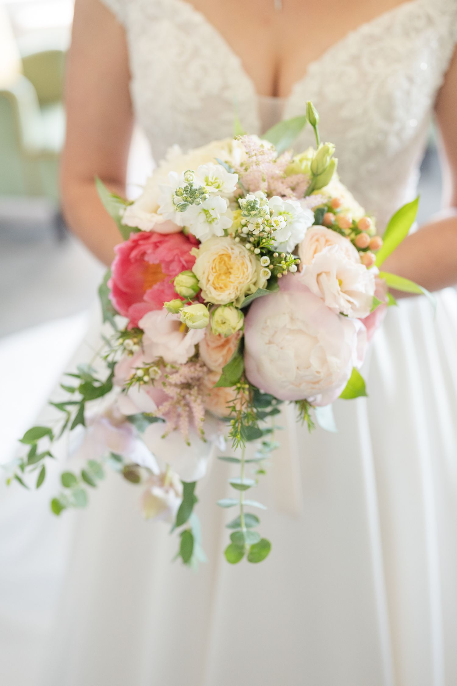 Delicate pastel bouquet with pink peonies, white flowers and eucalyptus greenery against a soft background.