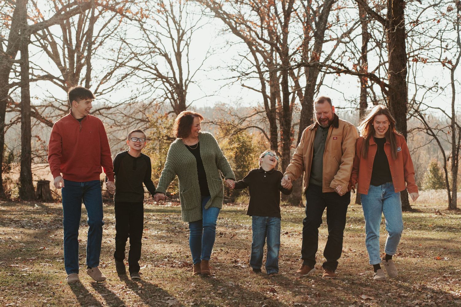 family walking through grass holding hands